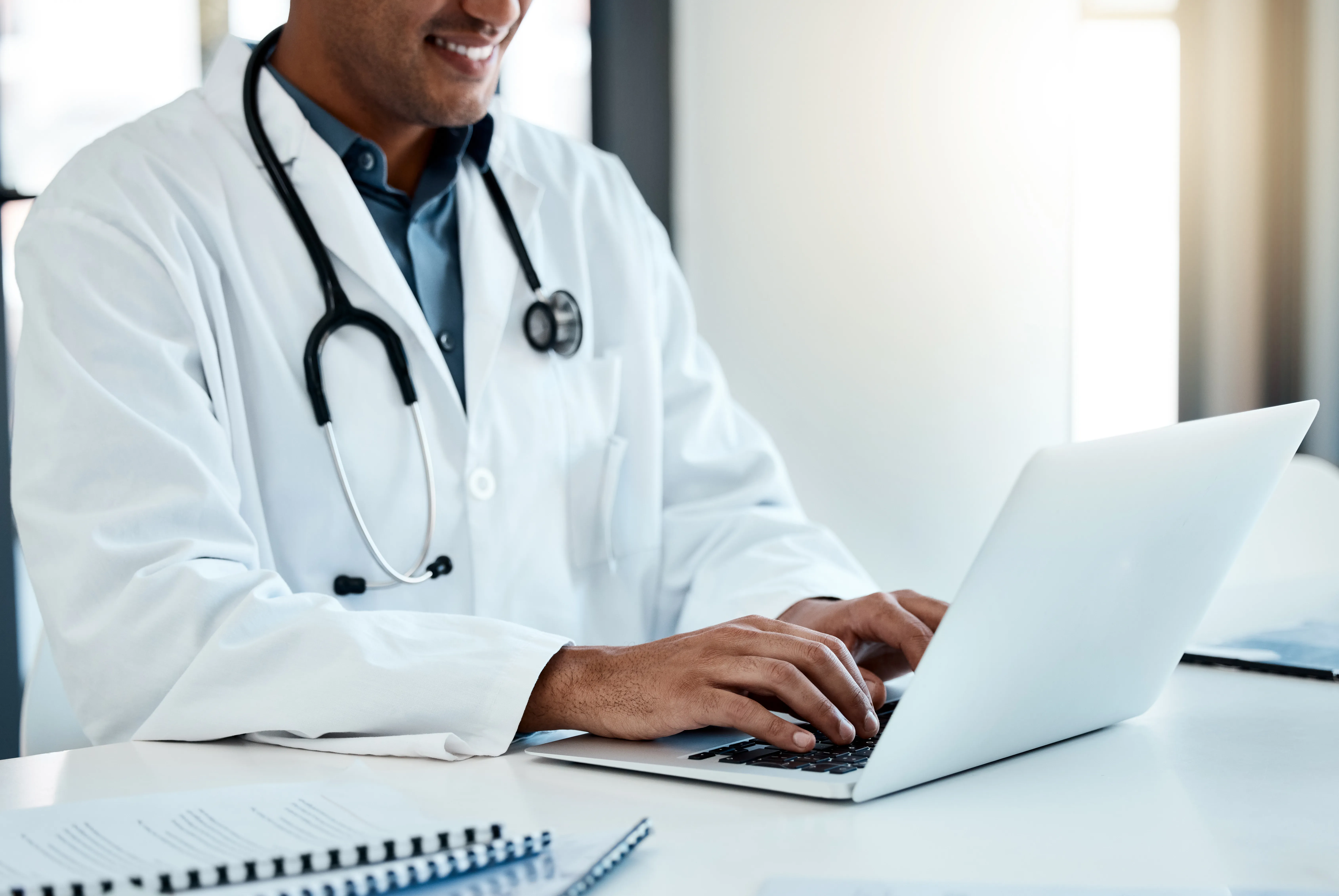 Doctor reviewing marketing reports on a laptop in a bright office